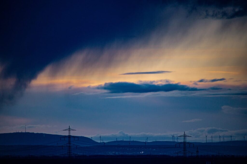 A group of wind mills in the distance under a cloudy sky