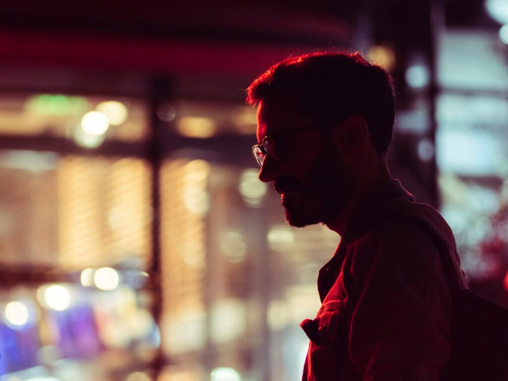 A man with glasses and a backpack standing in front of a building