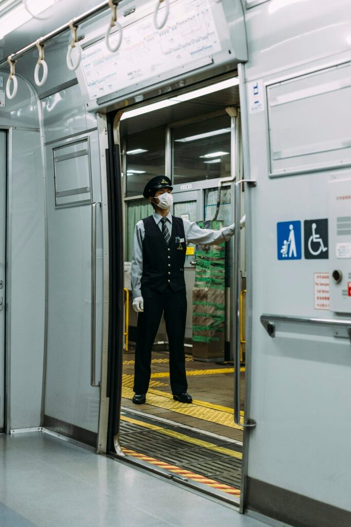 Male guard in black and white dress standing infront of train station