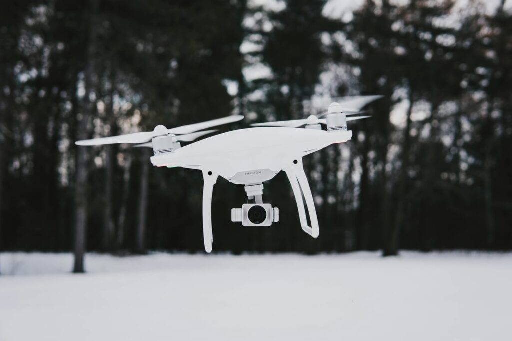 Flying quadcopter drone near trees during winter